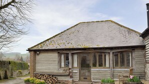 A rustic wooden house with a sloped roof, a front porch, and a gravel driveway.