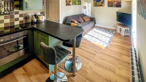 A compact living space with a kitchenette, a sofa, and a TV. - 1 bedroom accommodation in North Newton (North Newton)