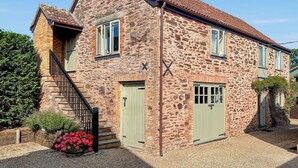 A stone house with a steeply pitched roof, a small staircase, and a gravel driveway. - 1 bedroom accommodation in North Newton (North Newton)