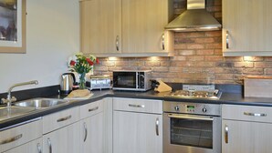 A modern kitchen with stainless steel appliances, wooden cabinets, and a brick wall backsplash.