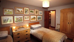Un dormitorio con dos camas, muebles de madera, cuadros enmarcados en la pared y un armario de madera.