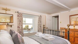 A bedroom with a bed, a dresser, a window with curtains, and a door. - 1 bedroom accommodation in Keswick (Keswick)