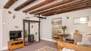 A living room with a fireplace, wooden beams, a television, a sofa, and a rug. - 1 bedroom accommodation in Keswick (Keswick)