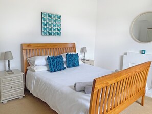 A neatly made bed with white bedding and two blue pillows, a wooden headboard, a bedside table with a lamp, and a wall-mounted mirror. - 3 bedroom accommodation in Kilmichael Glassary, near Lochgilphead (Kilmichael Glassary, near Lochgilphead)
