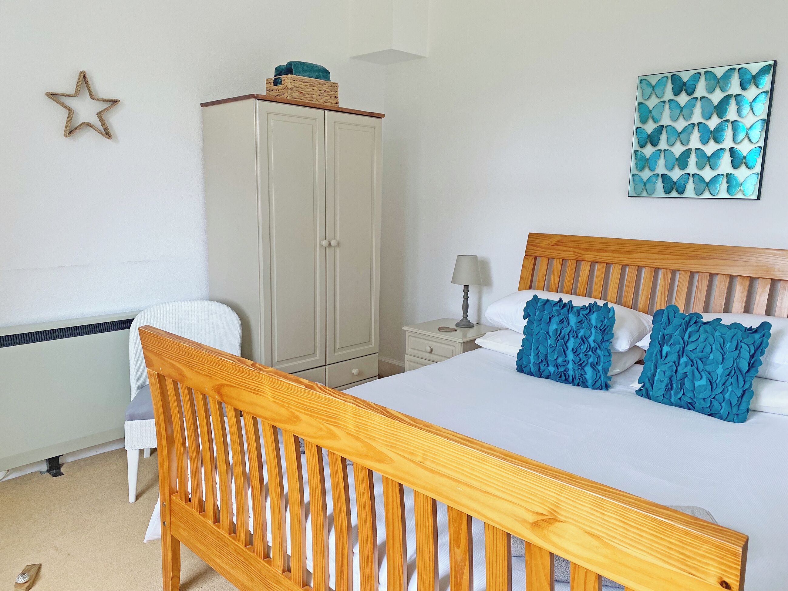 Une chambre à coucher avec un lit en bois, une table de chevet avec une lampe, une armoire et un élément décoratif mural.