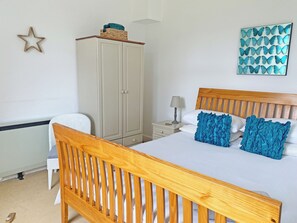 A bedroom with a wooden bed frame, a nightstand with a lamp, a wardrobe, and a wall decoration.