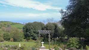 En have med pergola, statue og forskellige planter.