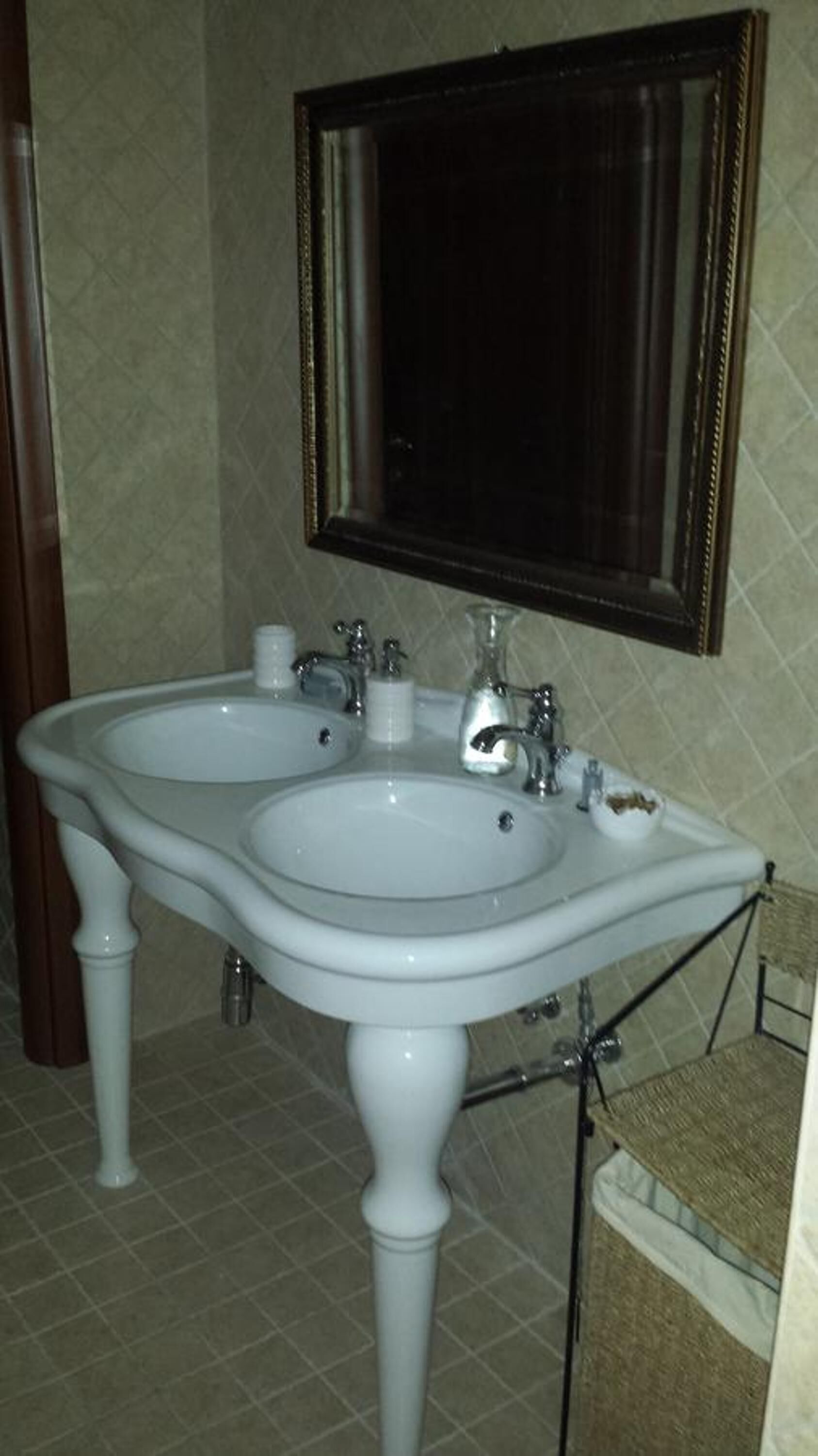 A bathroom with a double sink, a mirror, and a towel rack.