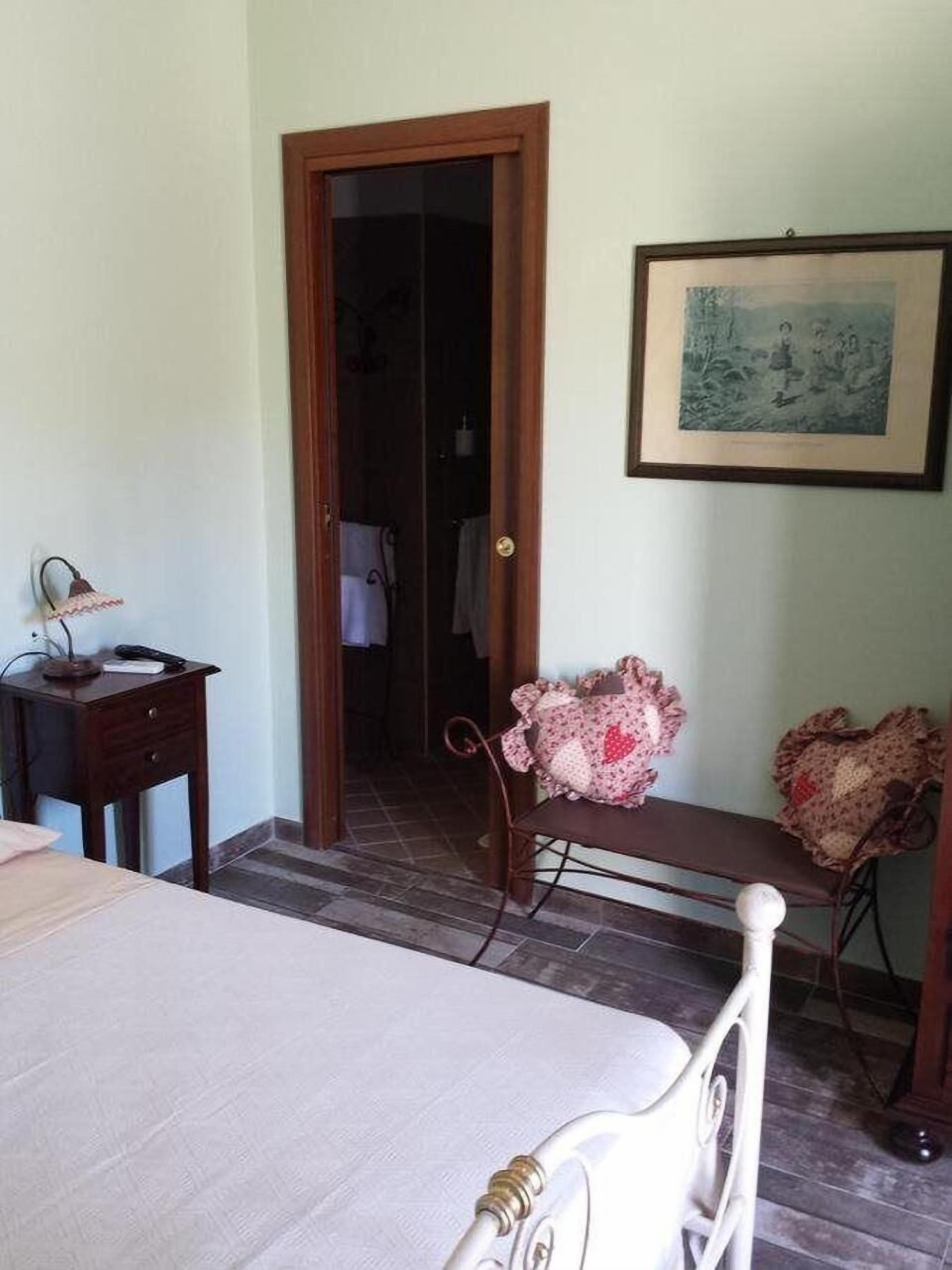 Un dormitorio con cama, escritorio, silla, puerta y un cuadro en la pared.
