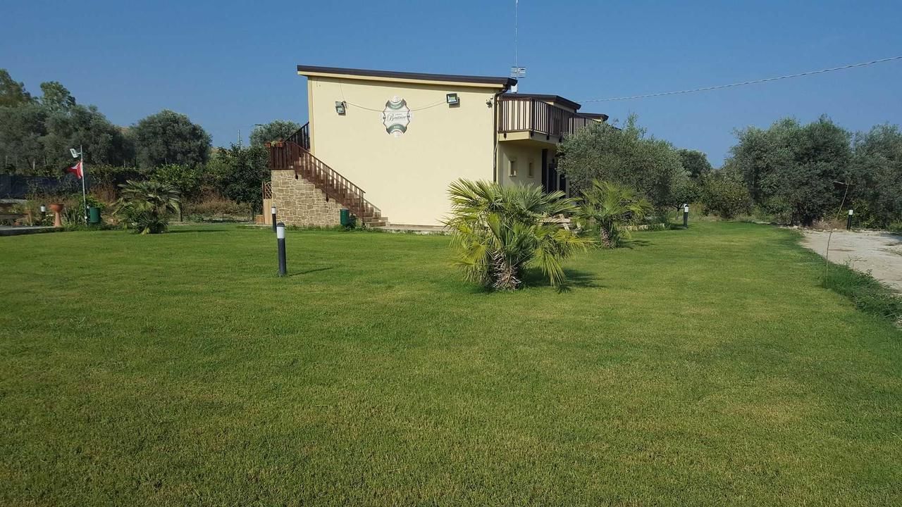 Un edificio con un balcone, una scala e un piccolo giardino con palme.
