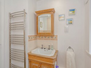 Une salle de bain avec un meuble-lavabo en bois, un évier, un miroir, un porte-serviettes et une serviette.