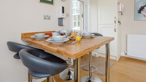 Un coin repas avec une table en bois, des chaises noires et une porte blanche.