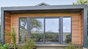 Ein modernes Gebäude mit großen Glasüren, Holzverkleidung und einer kleinen Treppe zum Eingang.