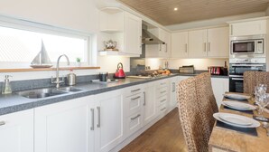 A modern kitchen with white cabinets, a granite countertop, and stainless steel appliances. - Swedish timber-style house, with sauna and hot tub, on a 400-acre estate. (Fritton, near Great Yarmouth)