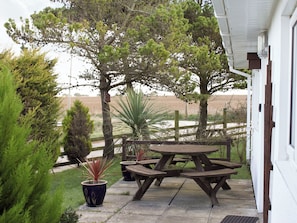 A patio with picnic tables, potted plants, and a view of the surrounding landscape. - Enjoy distant sea views whilst relaxing amidst the stunning rural surroundings. (St Merryn, near Padstow)