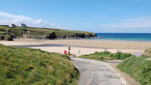 A coastal road leading to a beach with houses on a grassy hill. - Enjoy distant sea views whilst relaxing amidst the stunning rural surroundings. (St Merryn, near Padstow)