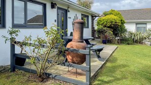 A white building with large windows, a patio with a table and chairs, and a large terracotta pot. - Enjoy distant sea views whilst relaxing amidst the stunning rural surroundings. (St Merryn, near Padstow)