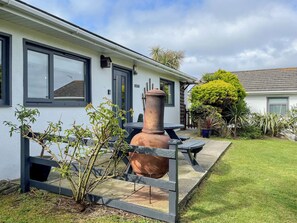 A white building with large windows, a patio with a table and chairs, and a large terracotta pot. - Enjoy distant sea views whilst relaxing amidst the stunning rural surroundings. (St Merryn, near Padstow)