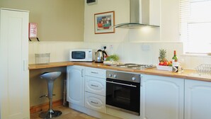 A compact kitchen with white cabinets, a microwave, an oven, and a sink. - Enjoy distant sea views whilst relaxing amidst the stunning rural surroundings. (St Merryn, near Padstow)