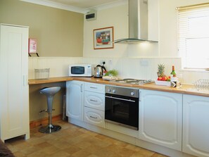 A compact kitchen with white cabinets, a microwave, an oven, and a sink. - Enjoy distant sea views whilst relaxing amidst the stunning rural surroundings. (St Merryn, near Padstow)