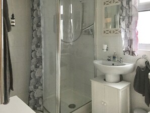 A bathroom with a glass shower enclosure, a white sink, and a mirror with a decorative frame. - Enjoy distant sea views whilst relaxing amidst the stunning rural surroundings. (St Merryn, near Padstow)