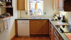 Una cocina con armarios de madera, un lavavajillas Bosch, una ventana con vistas y una encimera con electrodomésticos.