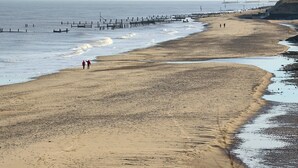 A beach with a wooden pier extending into the water, a sandy shore, and a few people walking. - 2 bedroom accommodation in Happisburgh, near Cromer (Happisburgh, near Cromer)