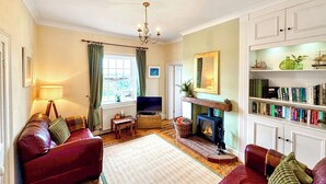 A cozy living room with a fireplace, a television, and a bookshelf. - 2 bedroom accommodation in Happisburgh, near Cromer (Happisburgh, near Cromer)