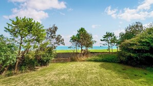 A grassy area with trees and a stone wall leading to a beach. - 2 bedroom accommodation in Happisburgh, near Cromer (Happisburgh, near Cromer)