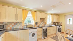A modern kitchen with wooden cabinets, a built-in microwave, a toaster, a washing machine, and a dishwasher. - 3 bedroom accommodation in Morecambe (Morecambe)