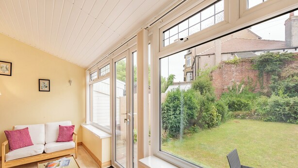 A cozy room with a white sofa, a small table with tea set, and a large window overlooking a garden. - 3 bedroom accommodation in Morecambe (Morecambe)