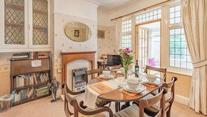 A dining room with a fireplace, wooden chairs, a table set for four, and a bookshelf with books. - 3 bedroom accommodation in Morecambe (Morecambe)