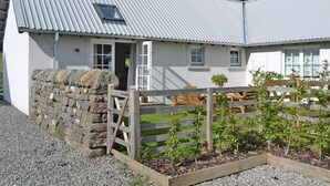 A white cottage with a stone wall, wooden gate, and a garden with plants. - 1 bedroom accommodation in near Comrie and Crieff (near Comrie and Crieff)