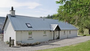 A white house with a metal roof, a chimney, and a small porch. - 1 bedroom accommodation in near Comrie and Crieff (near Comrie and Crieff)