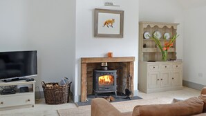 A living room with a fireplace, a television, and a cabinet with decorative plates. - 1 bedroom accommodation in near Comrie and Crieff (near Comrie and Crieff)