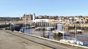 Un port avec des bateaux amarrés, un phare et un pont en arrière-plan.