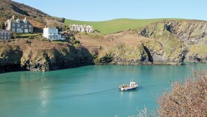 A coastal area with a large white building complex, a small boat anchored in the water, and a rocky hillside. - 2 bedroom accommodation in Port Isaac (Port Isaac)