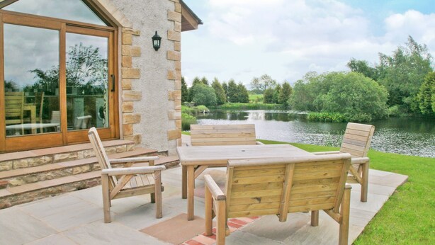 Un patio con muebles de madera y vista a un lago.