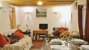 Un salon chaleureux avec un canapé, un fauteuil et une table à manger dressée pour le repas.