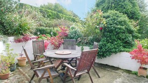 A round wooden table with four chairs, surrounded by potted plants and a white wall. - 3 bedroom accommodation in Potterne, near Devizes (Potterne, near Devizes)