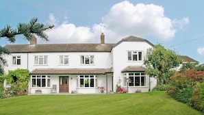A two-story house with a front porch, a chimney, and a well-maintained lawn. - 3 bedroom accommodation in Potterne, near Devizes (Potterne, near Devizes)