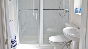 Une salle de bain avec une douche à parois de verre, des toilettes blanches et un lavabo.
