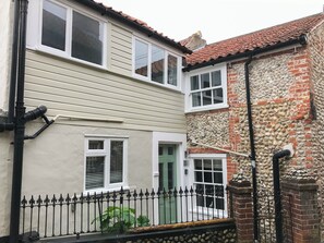 A two-story house with a stone facade and a metal fence.