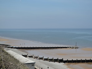 A coastal beach with a concrete walkway and a wooden breakwater.