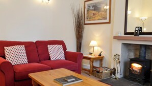 A living room with a red sofa, a wooden coffee table, a fireplace, and a lamp.