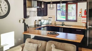 Una cocina moderna con encimera de madera, horno empotrado y lavamanos. En primer plano, un sofá con cojines decorativos.