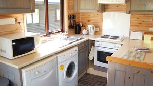 Une cuisine compacte équipée d’un four à micro-ondes, d’un lave-linge, d’une cuisinière et d’un évier.