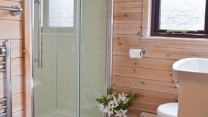 Une salle de bain avec un intérieur en bois, une douche en verre, des toilettes et un lavabo.