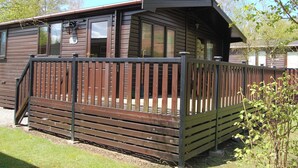 Une cabane en bois dotée d’une terrasse, de grandes fenêtres et d’un porche abrité.