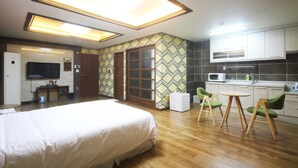 A hotel room with a large bed, a kitchenette, a dining area with chairs, and a TV. - W Motel (Tongyeong)